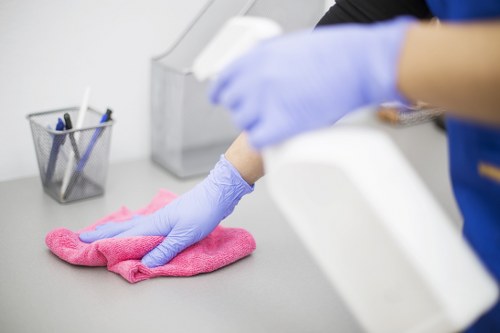 Professional cleaner tidying a Putney office workspace and shared areas